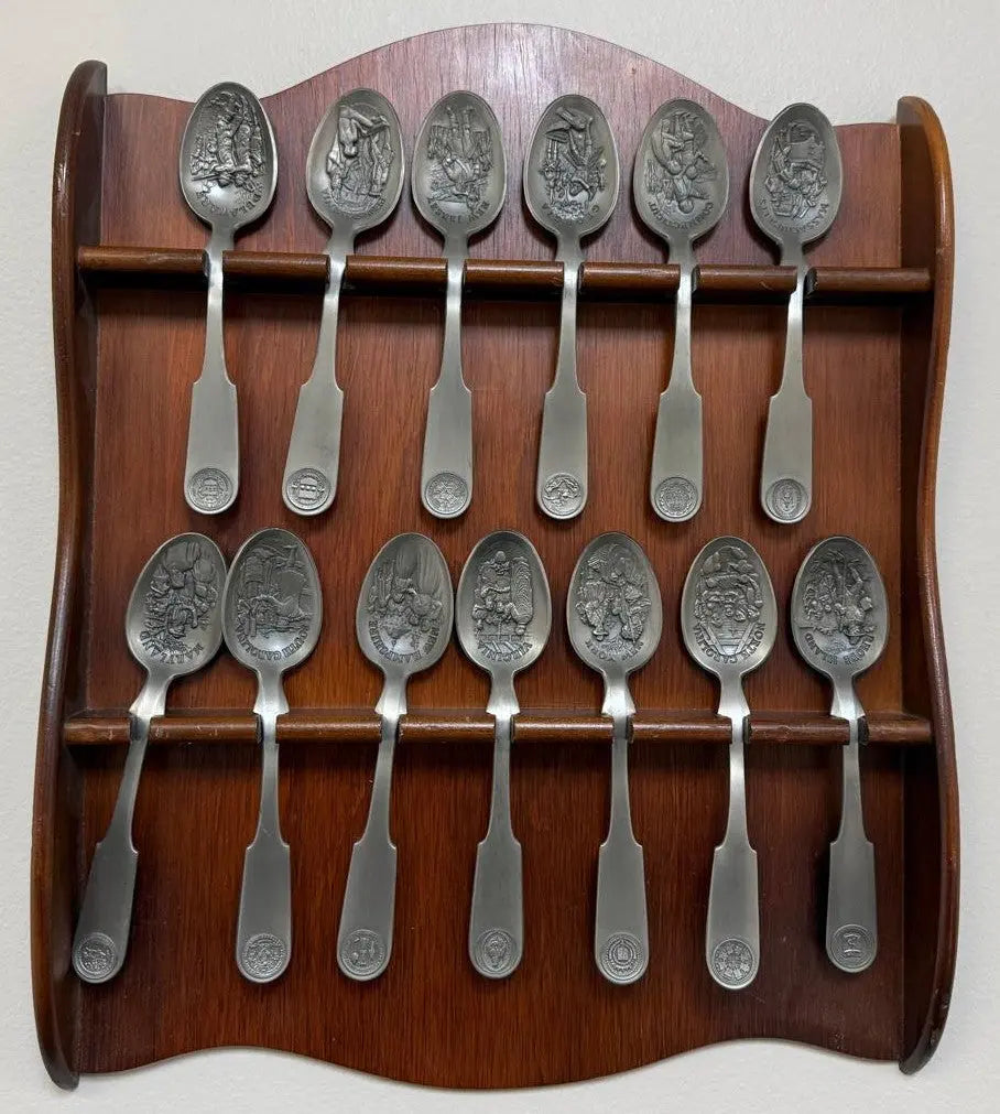 Franklin Mint 13 Original American Colonies pewter spoons with a wooden display rack.
